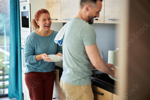 Cheerful spouces washing plates in kitchen stock photo