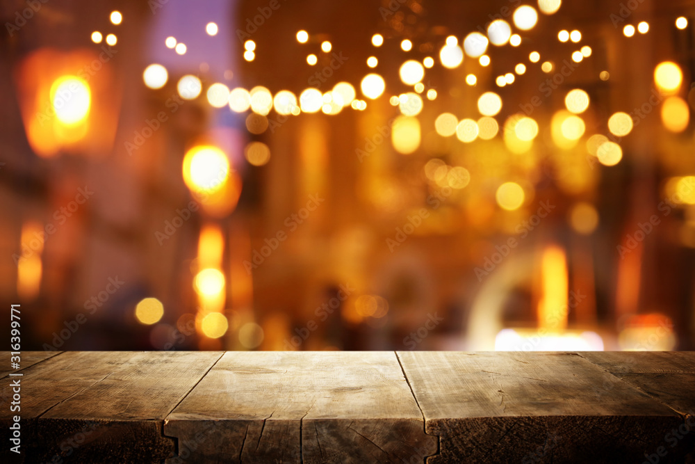 background Image of wooden table in front of abstract blurred restaurant lights background Image of wooden table in front of abstract blurred restaurant lights