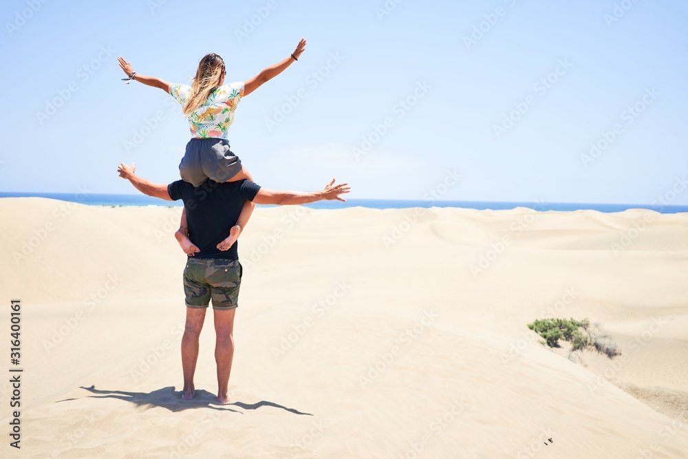 Young beautiful couple smiling happy and confident. Woman sitting on man shoulders with smile on face at the beach Young beautiful couple smiling happy and confident. Woman sitting on man shoulders with smile on face at the beach