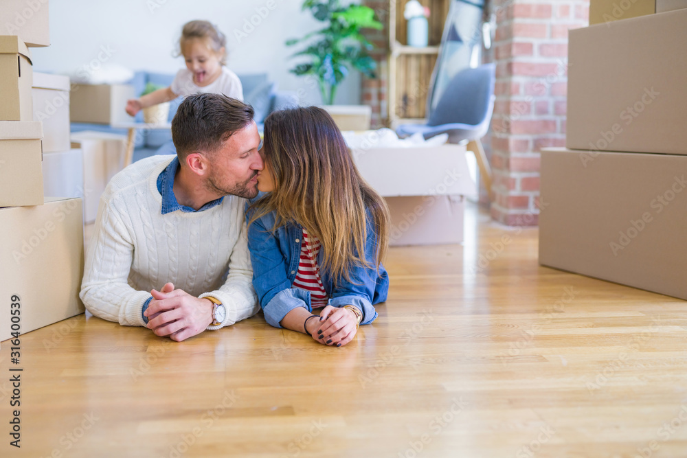 Beautiful famiily with kid lying down at new home around cardboard boxes Beautiful famiily with kid lying down at new home around cardboard boxes
