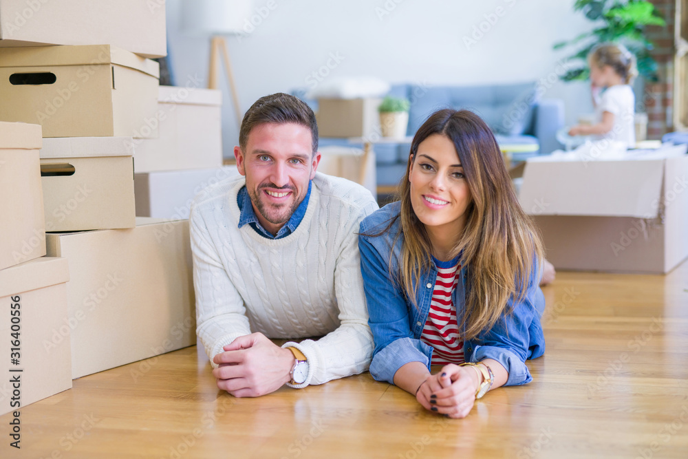 Beautiful famiily with kid lying down at new home around cardboard boxes Beautiful famiily with kid lying down at new home around cardboard boxes
