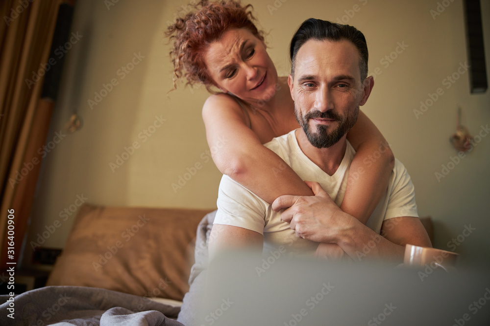Obraz premium Happy adult couple having fun in the bedroom at home