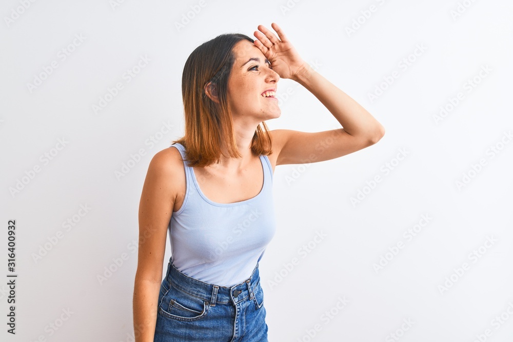 Beautiful redhead woman standing over isolated background very happy and smiling looking far away with hand over head. Searching concept. Beautiful redhead woman standing over isolated background very happy and smiling looking far away with hand over head. Searching concept.