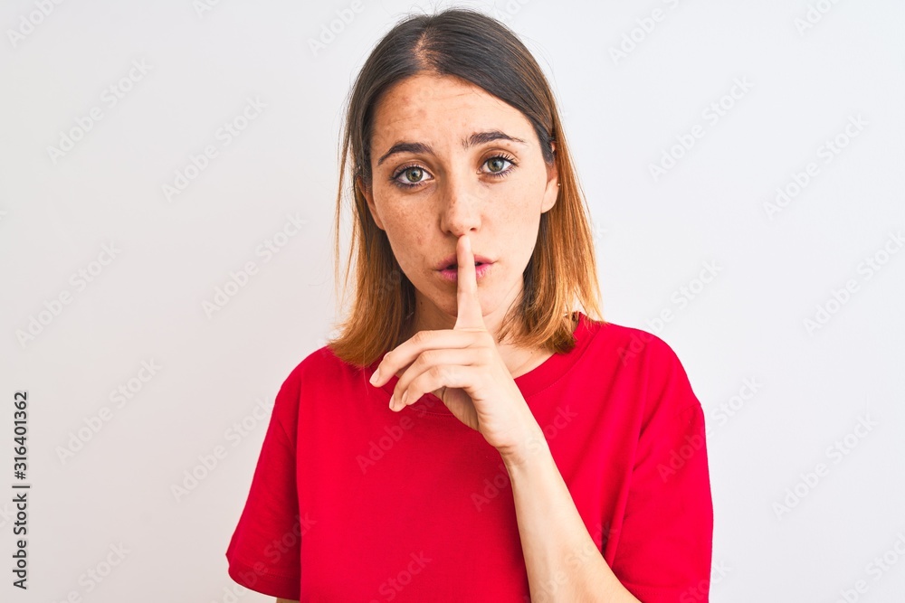 Beautiful redhead woman wearing casual red t-shirt over isolated background asking to be quiet with finger on lips. Silence and secret concept. Beautiful redhead woman wearing casual red t-shirt over isolated background asking to be quiet with finger on lips. Silence and secret concept.