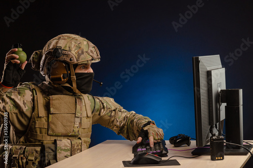 military in uniform sitting at a computer are cyberwar, playing, throwing a grenade photo