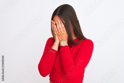 Young beautiful girl wearing red casual t-shirt standing over isolated white background with sad expression covering face with hands while crying. Depression concept.