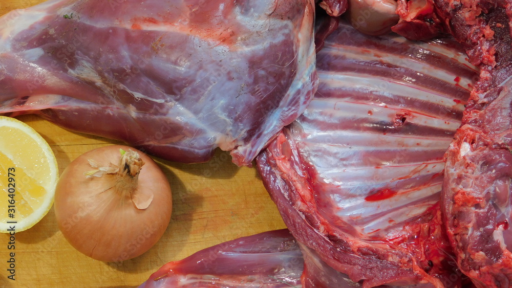 hare carcass butchered on a wooden Board with onions close up