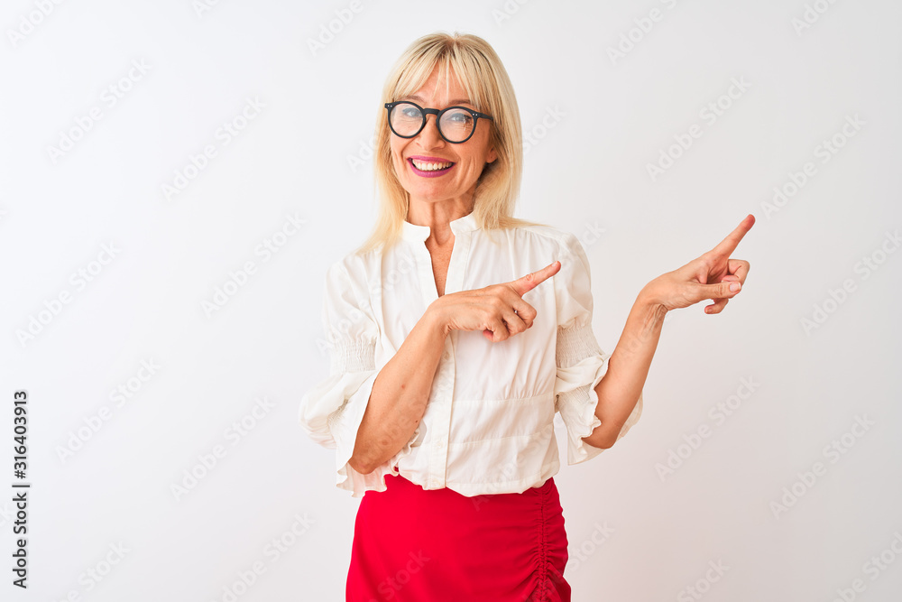 Obraz premium Middle age businesswoman wearing shirt and glasses standing over isolated white background smiling and looking at the camera pointing with two hands and fingers to the side.