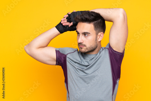 Sport man over isolated yellow wall stretching arm