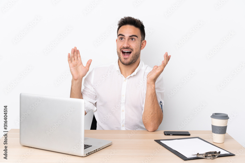 Young business man with a mobile phone in a workplace with surprise facial expression Young business man with a mobile phone in a workplace with surprise facial expression