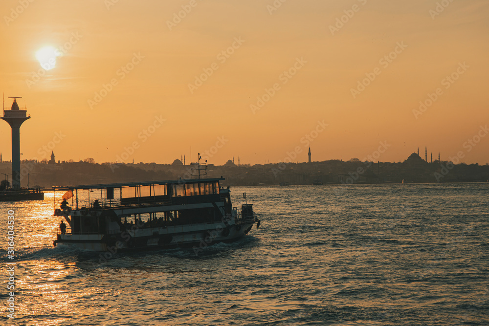 Istanbul Bosporus and city ferries with the silhouette of Hagia Sophia during sunset golden hour