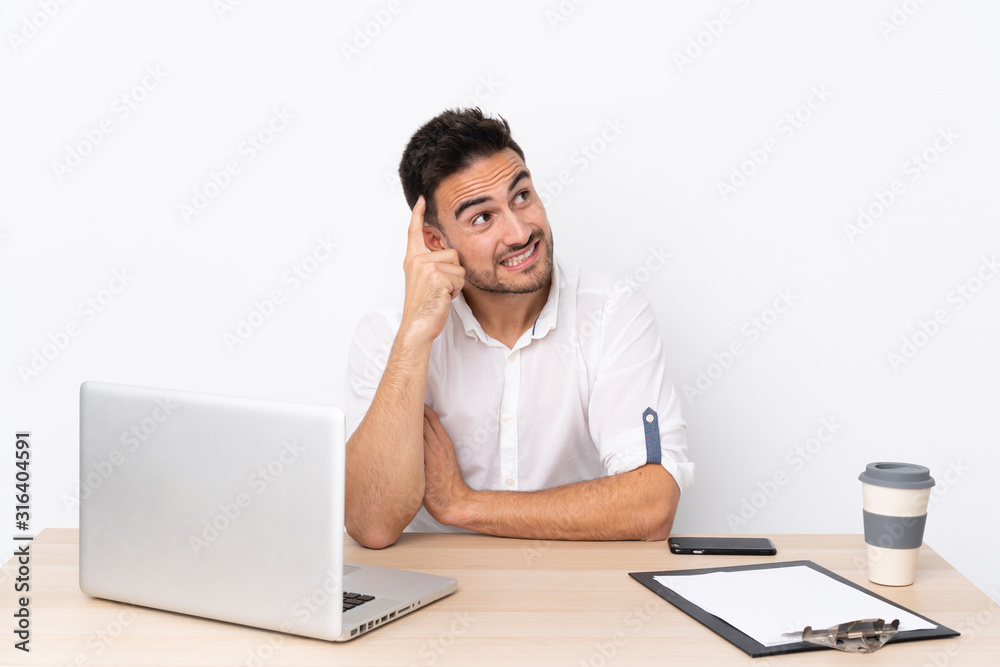 Young business man with a mobile phone in a workplace having doubts and with confuse face expression Young business man with a mobile phone in a workplace having doubts and with confuse face expression