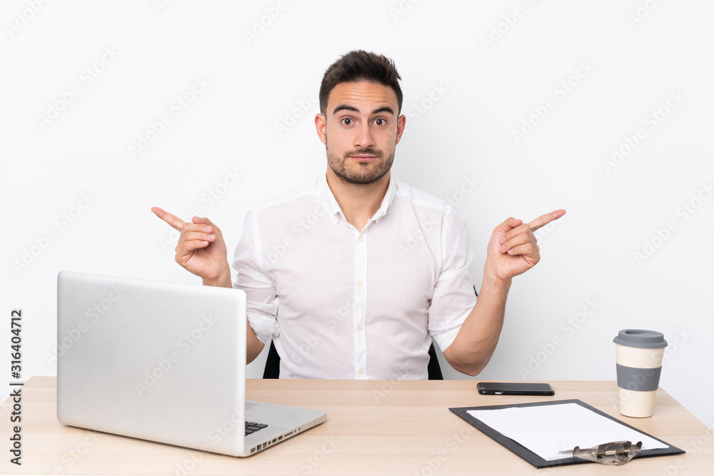 Young business man with a mobile phone in a workplace pointing to the laterals having doubts Young business man with a mobile phone in a workplace pointing to the laterals having doubts