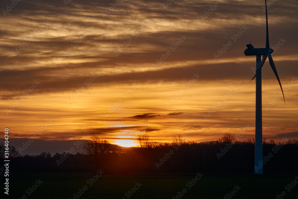 Obraz premium Concept picture climate change, rising sun behind the silhouette of a wind turbine