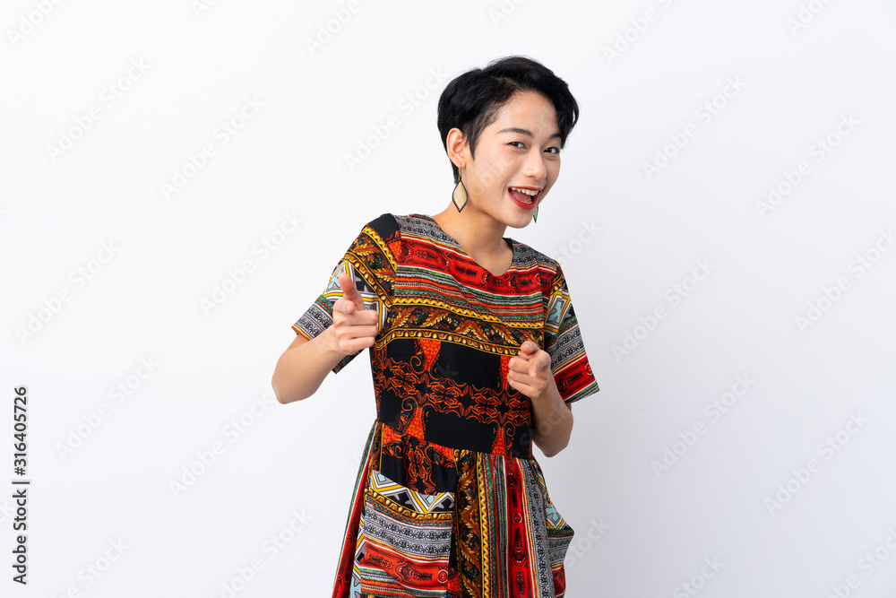 Young Asian girl with a colorful dress over isolated white background pointing to the front and smiling
