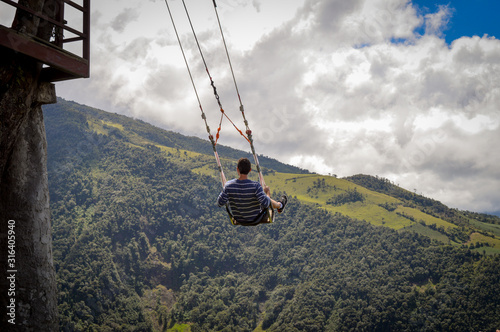 Boy swinging at a treehouse located on baños, ecuador. at the top of mountain. tungurahua volcano behind photo