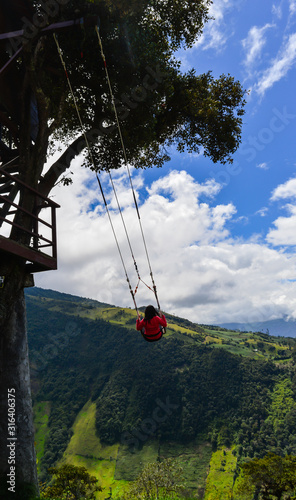 girl swinging at a treehouse located on baños, ecuador. at the top of mountain. tungurahua volcano behind photo