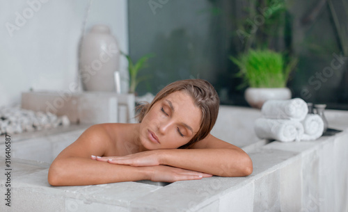 Young girl enjoys spa treatments in the bathroom with flowers.
