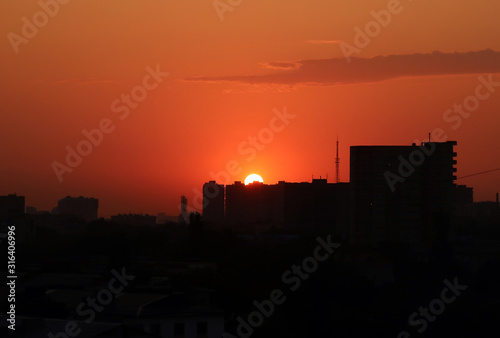 Bright orange sunset and big sun over the city on a hot sultry summer evening