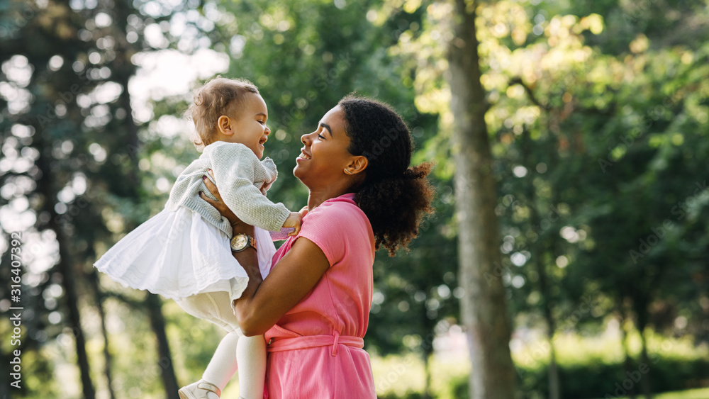 Mother and daughter having fun spending time together in the park. Woman lifting up her daughter. Mother and daughter having fun spending time together in the park. Woman lifting up her daughter.