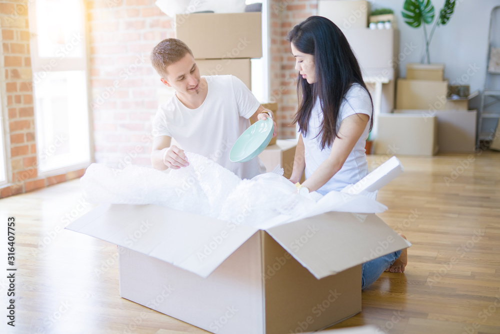Young beautiful couple open cardboard boxes to order new home Young beautiful couple open cardboard boxes to order new home