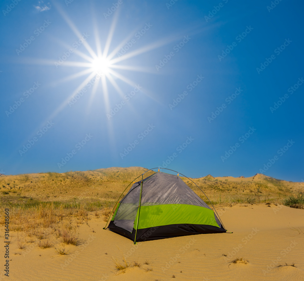 green touristic tent among sandy desert under a sparkle sun