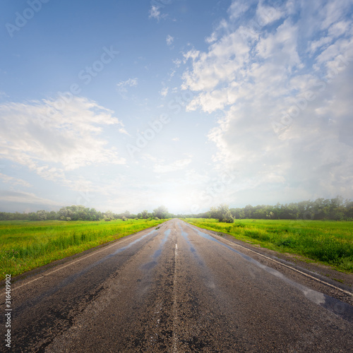 wet asphalt road after a rain in a light of sun © Yuriy Kulik