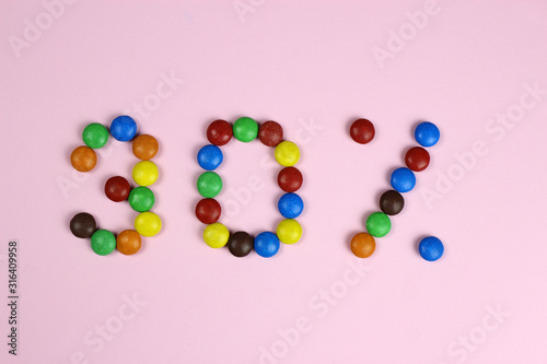 thirty percent of colored candy on a pink background