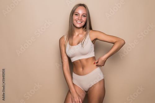 Young beautiful woman with with perfect body in nice lingerie on beige background.