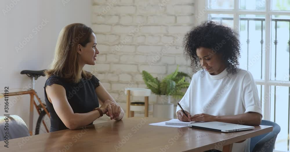 Satisfied businesswoman shaking hands with young african advisor. Satisfied businesswoman shaking hands with young african advisor.