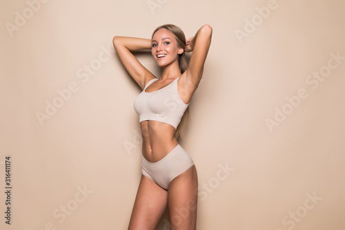 Leinwand Poster Young woman in underwear on beige background