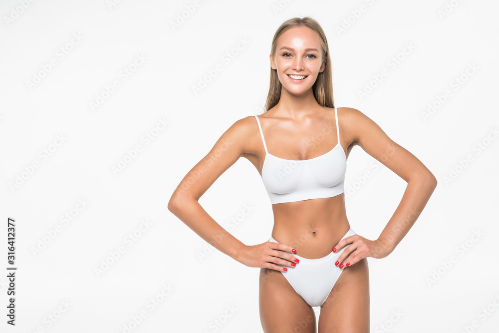 Proud of her perfect body. Attractive young brown hair woman in white lingerie posing against grey background.