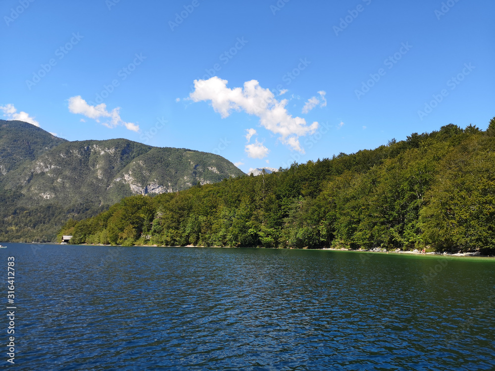 Beautiful view of the crystal clear Bohinj lake from the water with the mountains in the background