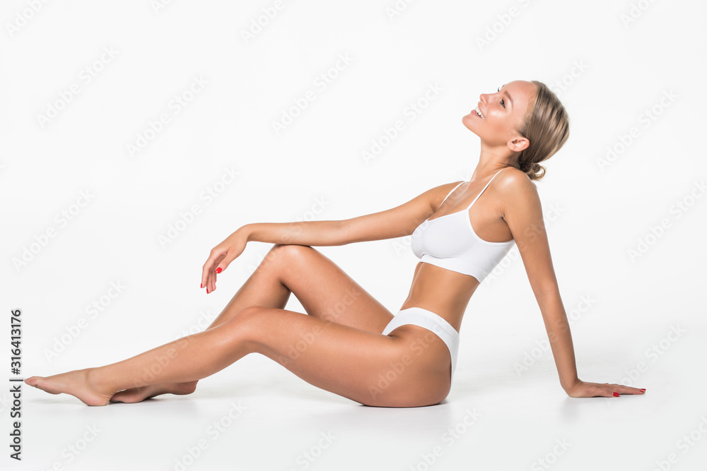 Wellness and beauty concept, beautiful slim woman in white underwear sitting on white floor isolated