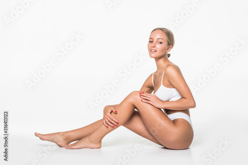 Wellness and beauty concept, beautiful slim woman in white underwear sitting on white floor isolated