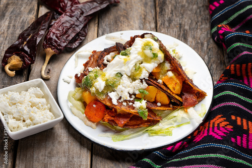 Mexican red enchiladas with potato and pork chorizo also called Potosinas on wooden background photo
