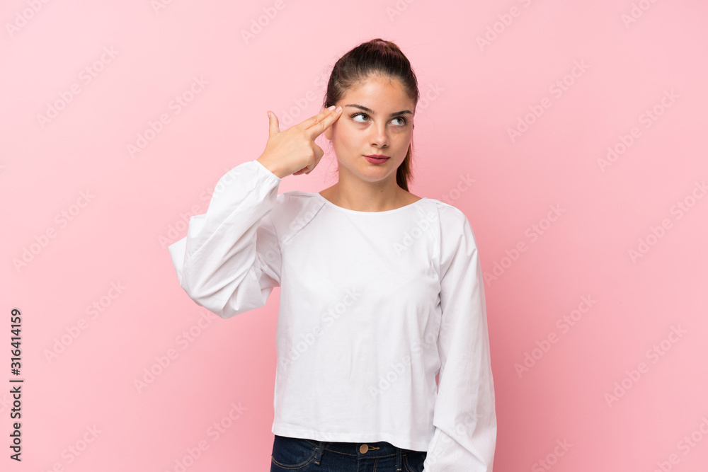 Young brunette girl over isolated pink background with problems making suicide gesture Young brunette girl over isolated pink background with problems making suicide gesture