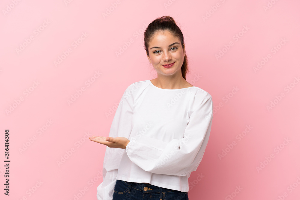 Young brunette girl over isolated pink background presenting an idea while looking smiling towards Young brunette girl over isolated pink background presenting an idea while looking smiling towards