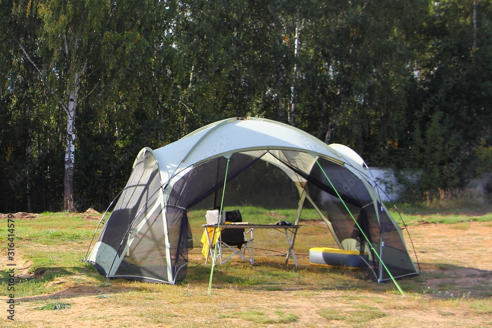 Empty open frame tent in a glade on a Sunny summer day, outdoor tourism recreation