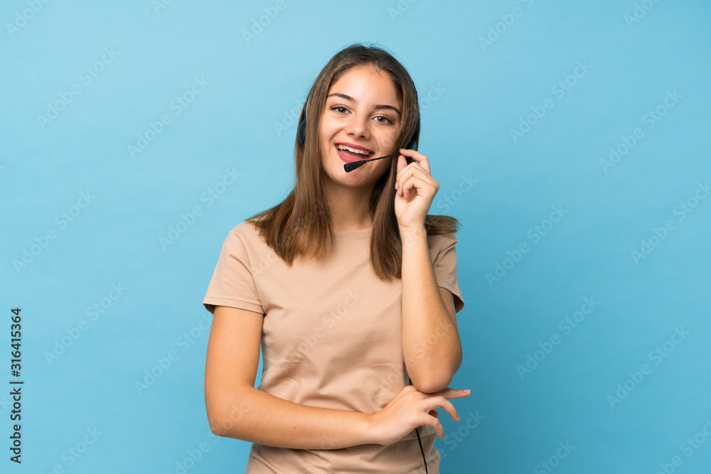 Fototapeta premium Young brunette girl over isolated blue background working with headset