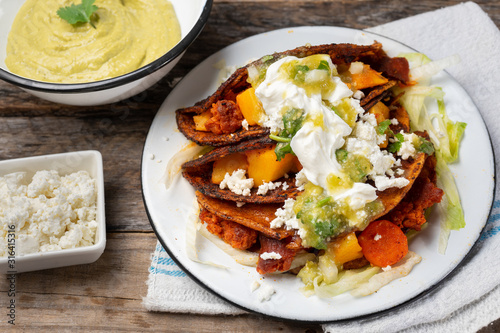 Mexican red enchiladas with potato and pork chorizo also called Potosinas on wooden background photo