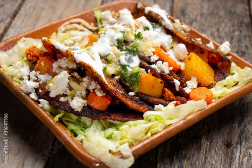 Mexican red enchiladas with potato and pork chorizo also called Potosinas on wooden background photo