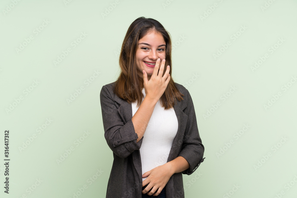 Young brunette girl with blazer over isolated green background smiling a lot Young brunette girl with blazer over isolated green background smiling a lot