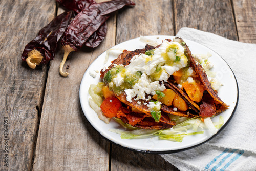 Mexican red enchiladas with potato and pork chorizo also called Potosinas on wooden background photo