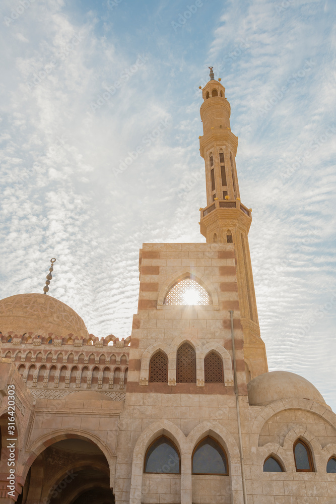 One of the main mosques in touristic city of Sharm el Sheikh, Egypt. Islamic faith concept. Against the backdrop of a beautiful blue sky with clouds. vertical photo