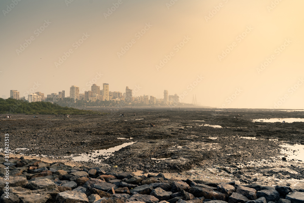 rocky beach at bandstand in mumbai from the rocky beach near joggers pack at sunset.