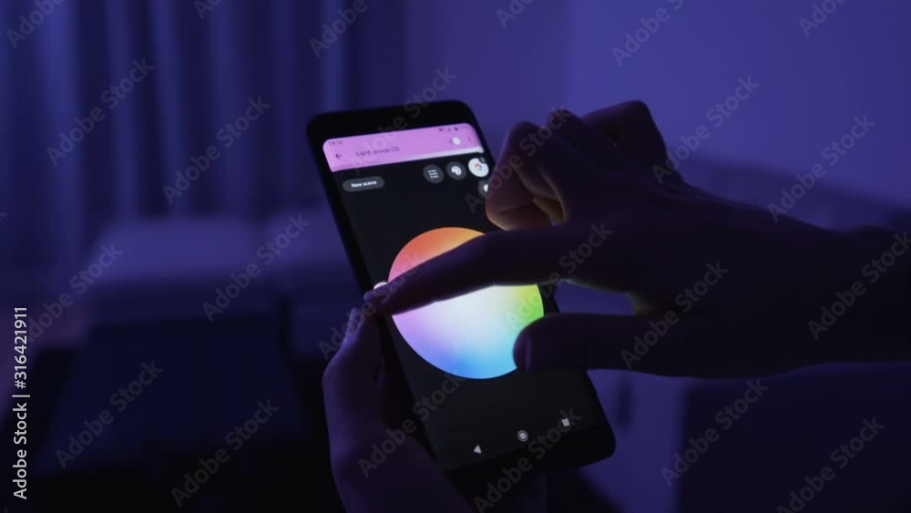 Young Woman Hand Phone Controlling  Modern Wi Fi Rgb Led Light Bulbs In Living Room Dark Nights Vibrant Colors Connectivity Concept 