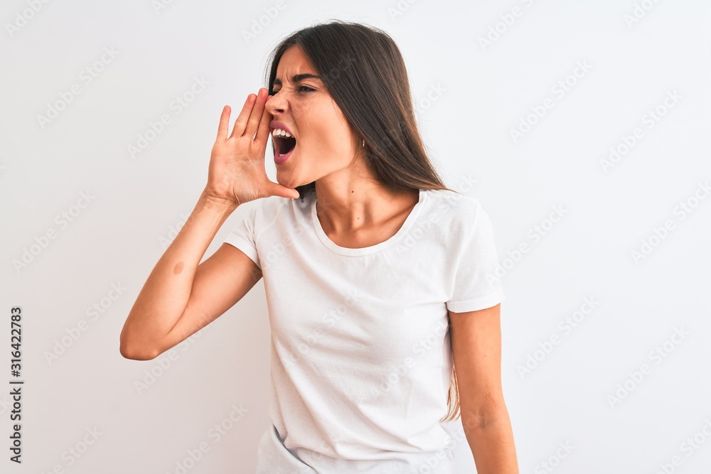 Young beautiful woman wearing casual t-shirt standing over isolated white background shouting and screaming loud to side with hand on mouth. Communication concept. Young beautiful woman wearing casual t-shirt standing over isolated white background shouting and screaming loud to side with hand on mouth. Communication concept.
