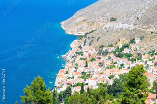 Fototapeta Naklejka Na Ścianę i Meble -  Picturesque detailed bird's eye view on tiny colorful houses on rocks on shore of Mediterranian sea on Greek island in sunny summer day, vacation on exotic islands