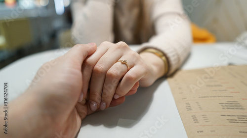 Woman hold man`s hand in her hands, woman has a wedding ring on her finger. Man making proposal with the ring to his girlfriend. Put ring on hand.